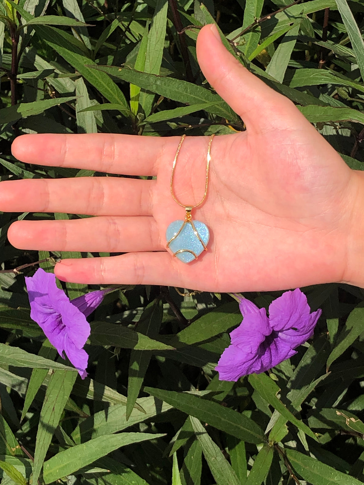 Blue heart pendant necklace displayed in hand