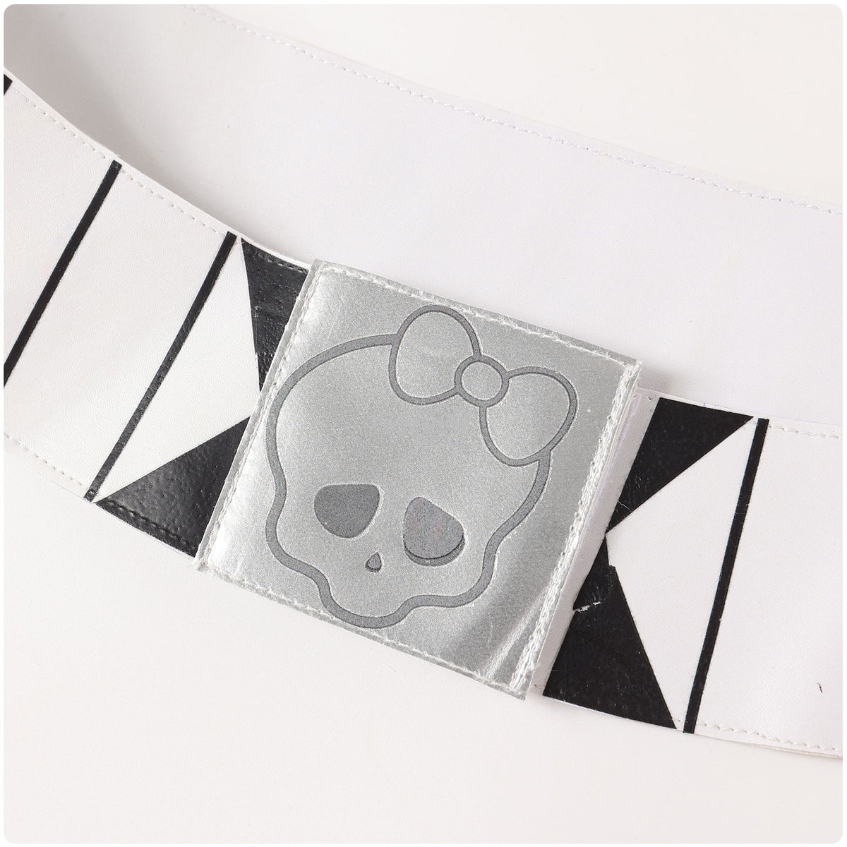 Close-up of the white belt with black graphic details and a silver-tone skull buckle
